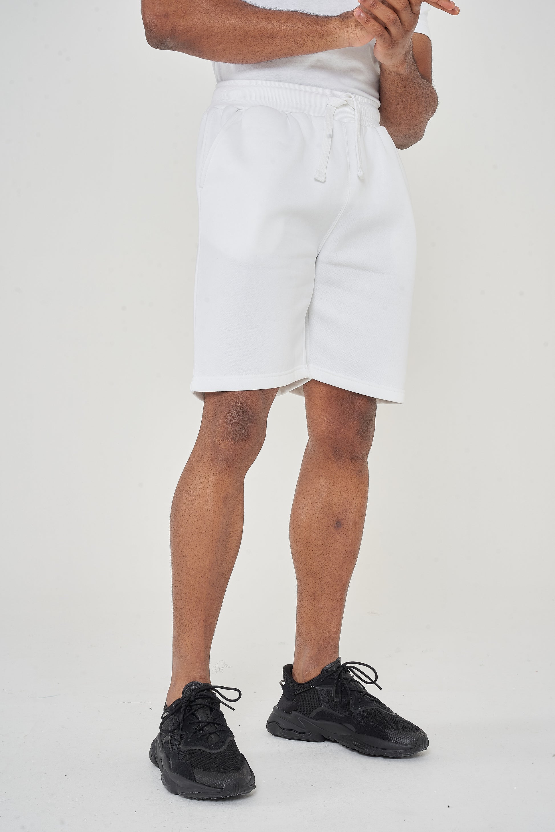 Model wearing men's white shorts from waist to feet with hands clasped, 365 Collection.