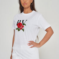 Woman wearing the white R &amp; V Rose Oversized T-Shirt styled with casual bottoms, highlighting the front rose print and comfortable, relaxed fit.