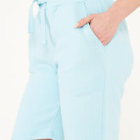 Side view of a woman in turquoise shorts showing length and relaxed style.