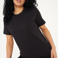 Woman wearing a basic black t-shirt with matching shorts, pictured front-facing. 