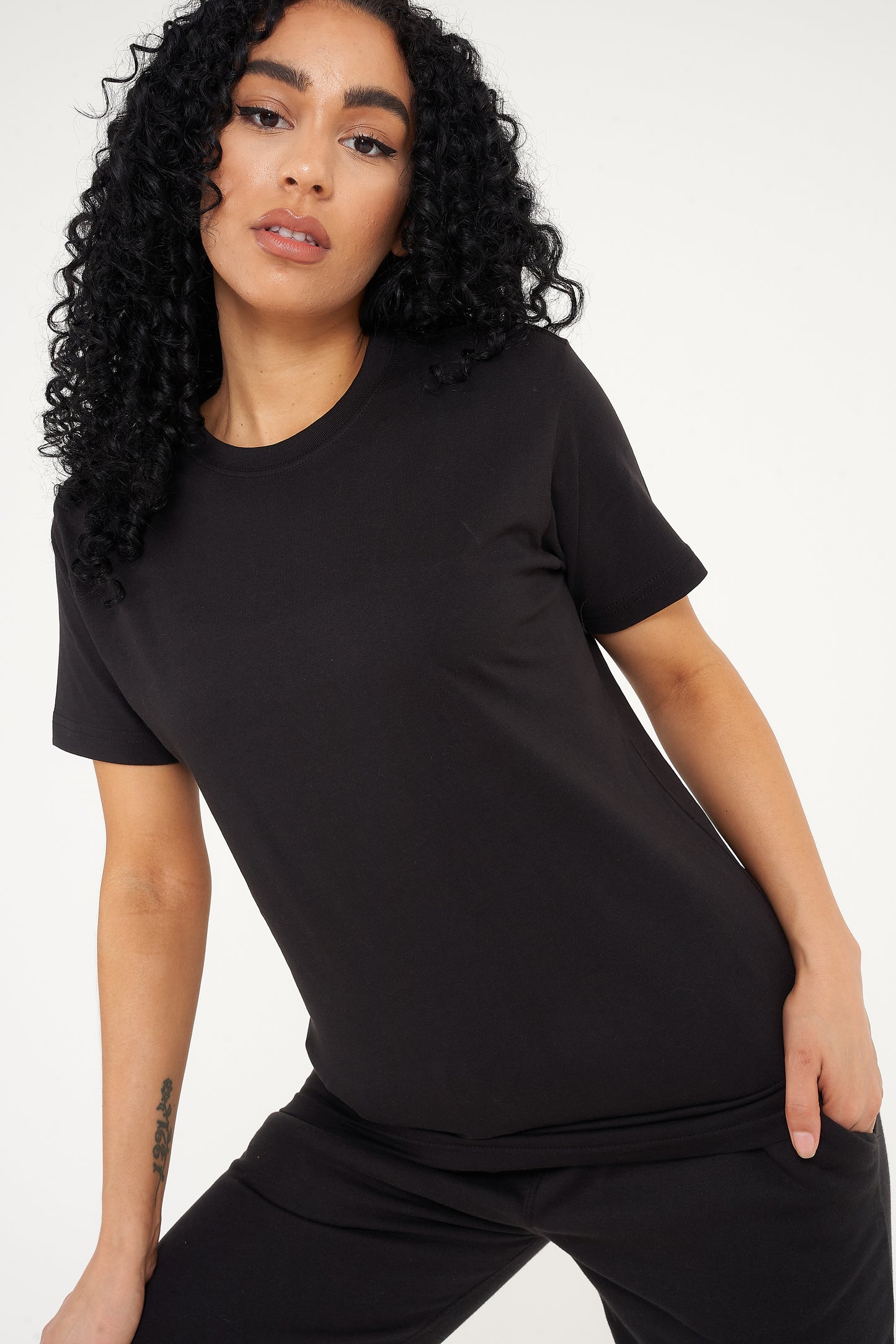 Woman wearing a basic black t-shirt with matching shorts, pictured front-facing. 