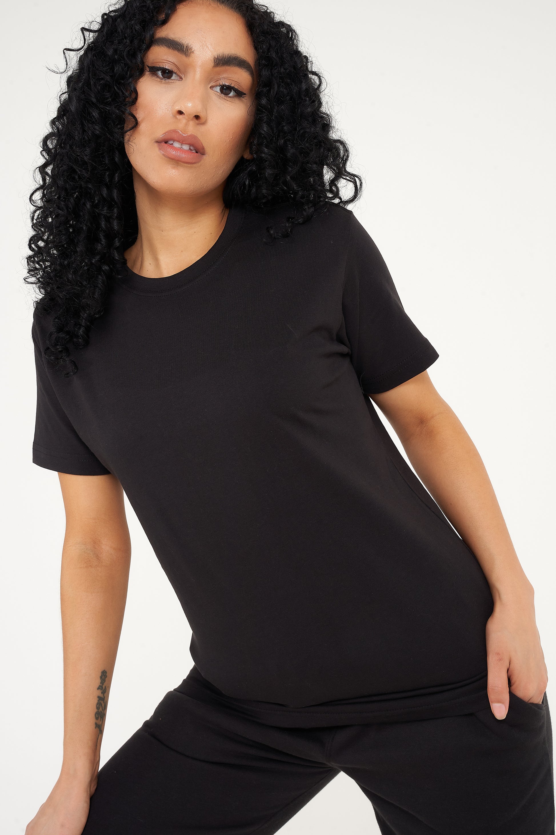 Woman wearing a basic black t-shirt with matching shorts, pictured front-facing. 