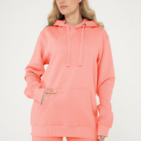 Woman modeling coral hoodie and shorts, front view with relaxed pose.