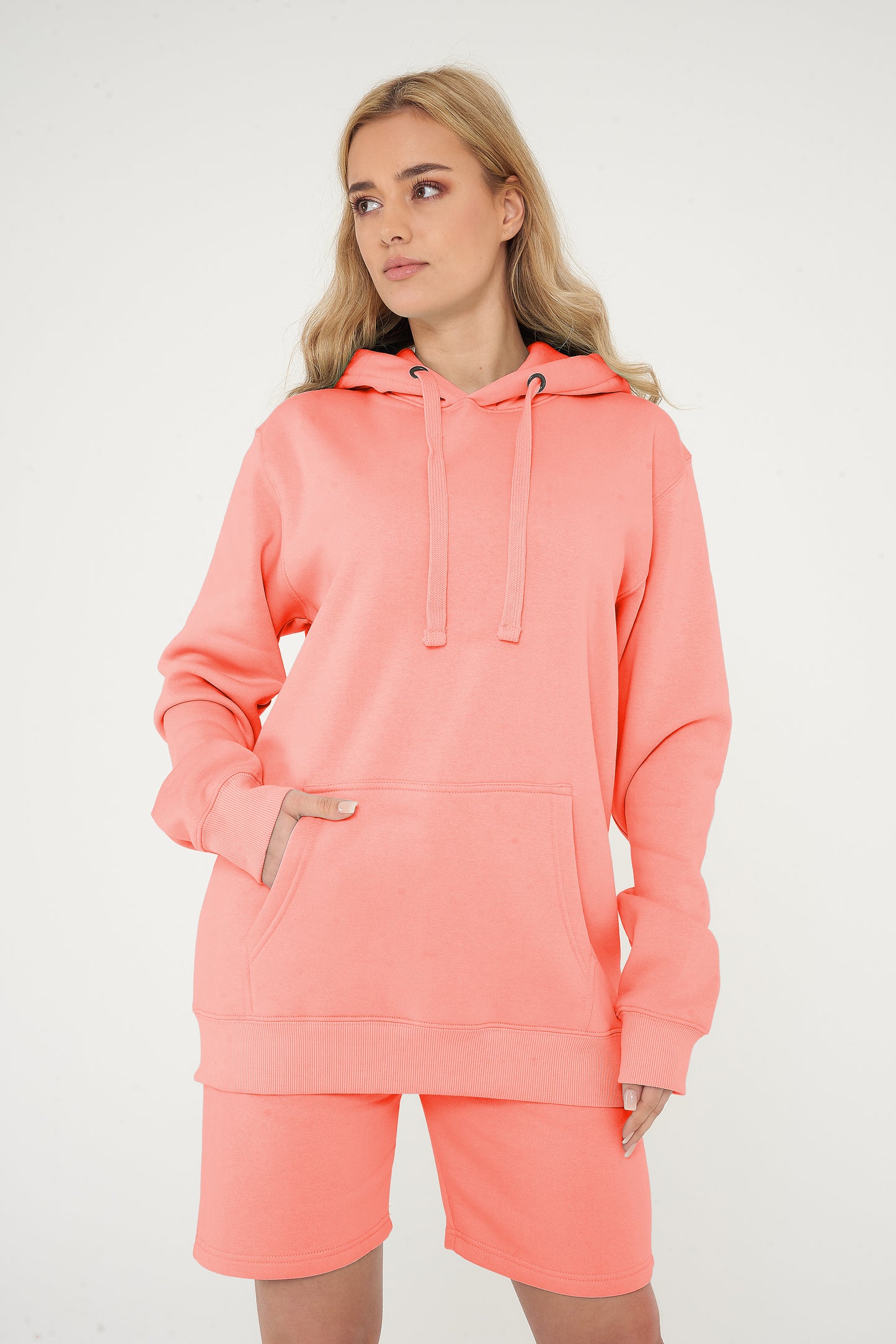 Woman modeling coral hoodie and shorts, front view with relaxed pose.
