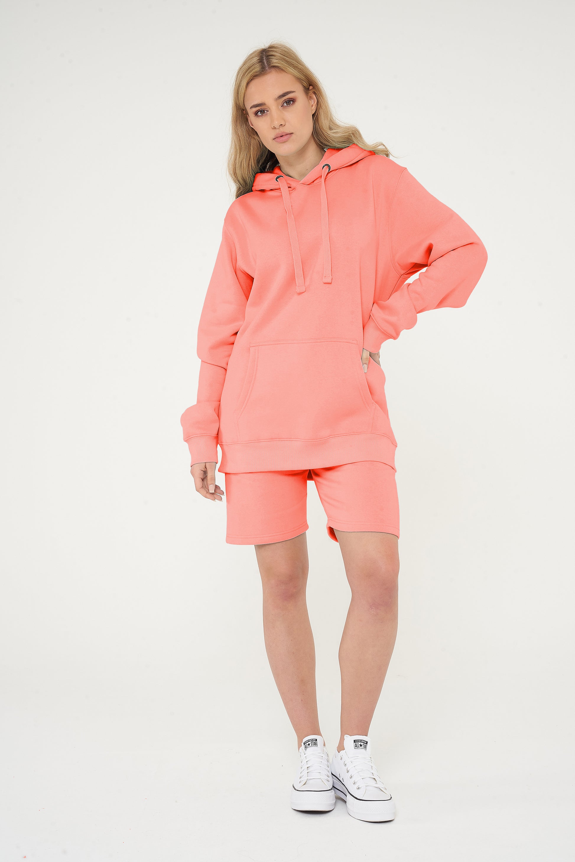 Woman wearing coral hoodie and matching shorts, front-facing, hands at sides.