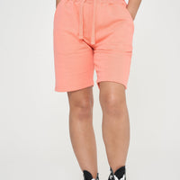 Woman wearing coral basic shorts and a t-shirt, front-facing pose.