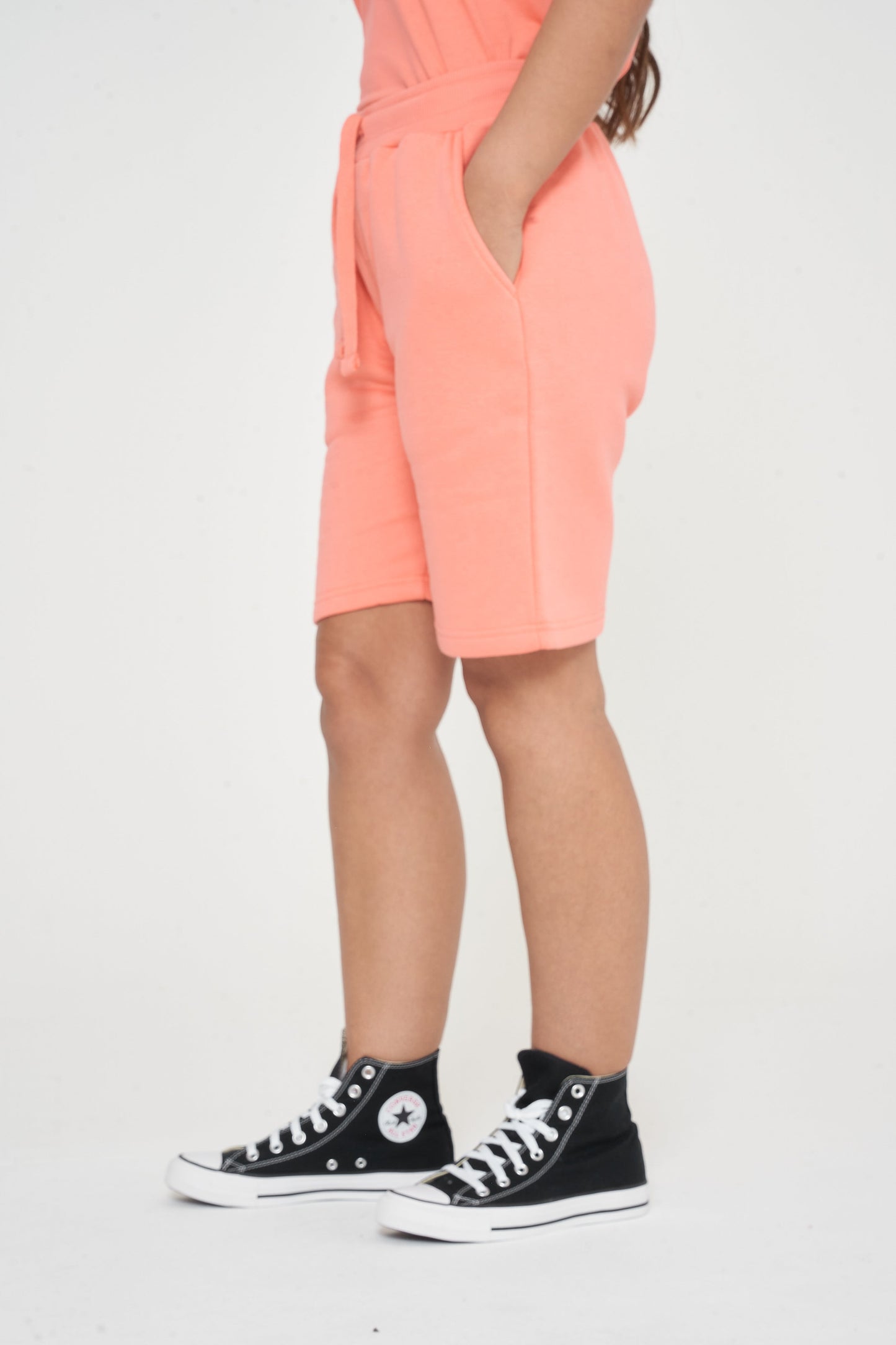 Side view of a woman in coral shorts showing length and comfortable fit. 