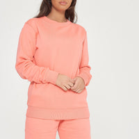 Woman modeling coral sweatshirt and shorts, side view showing fit and styling.