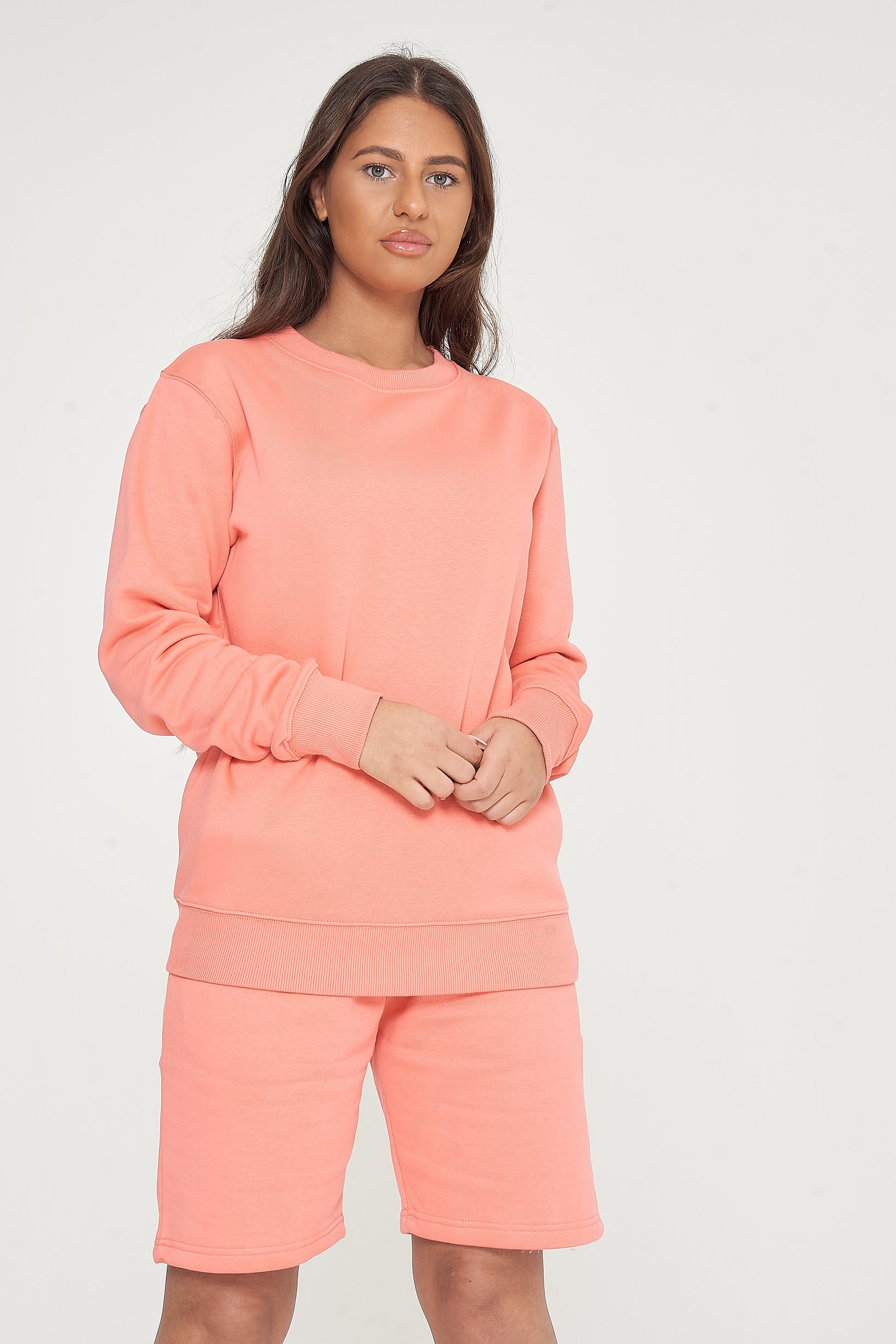 Woman modeling coral sweatshirt and shorts, side view showing fit and styling.