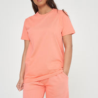 Woman modeling a coral t-shirt and shorts, side angle showing classic fit. 