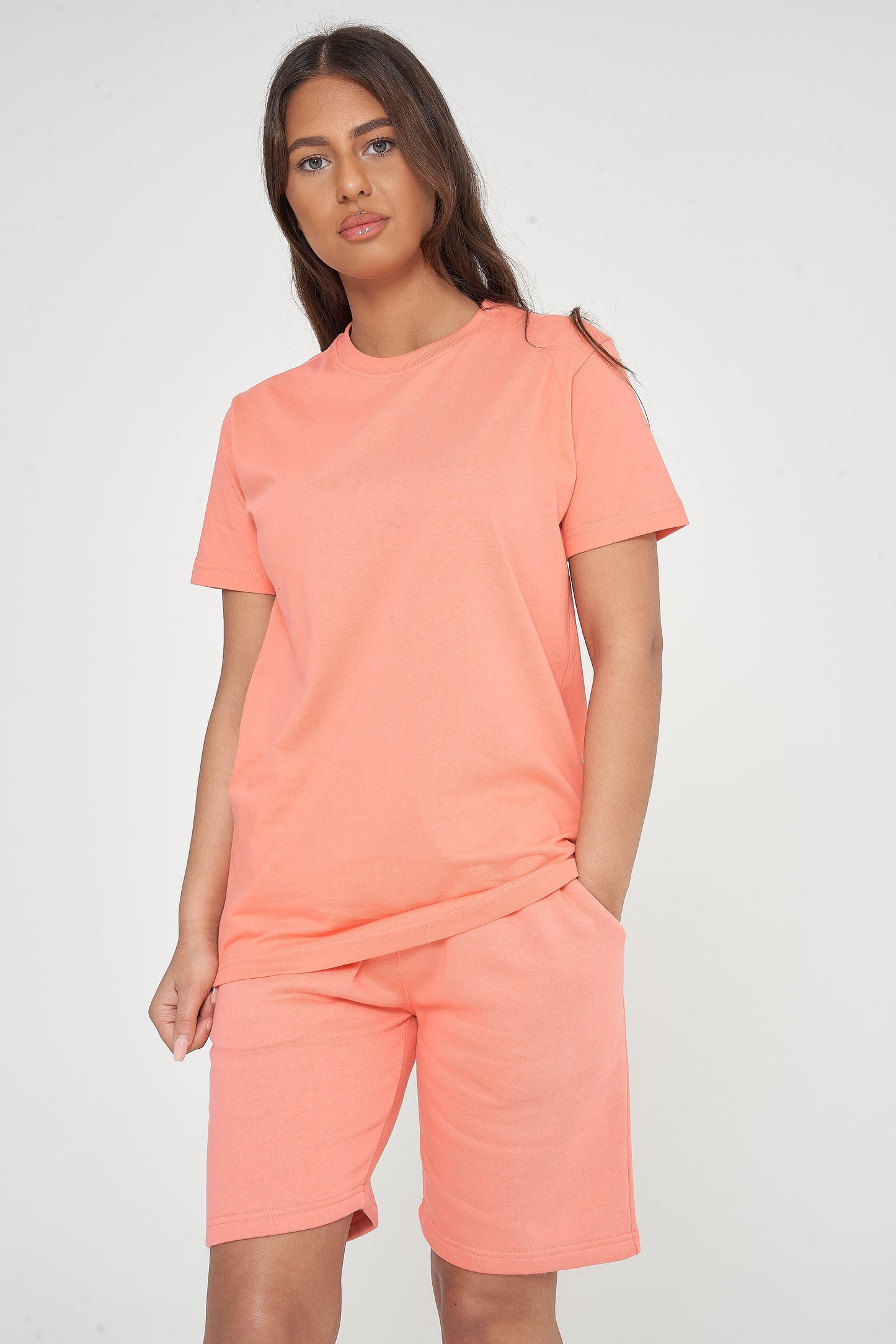 Woman modeling a coral t-shirt and shorts, side angle showing classic fit. 