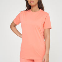 Woman wearing a basic coral t-shirt with matching shorts, front-facing pose.