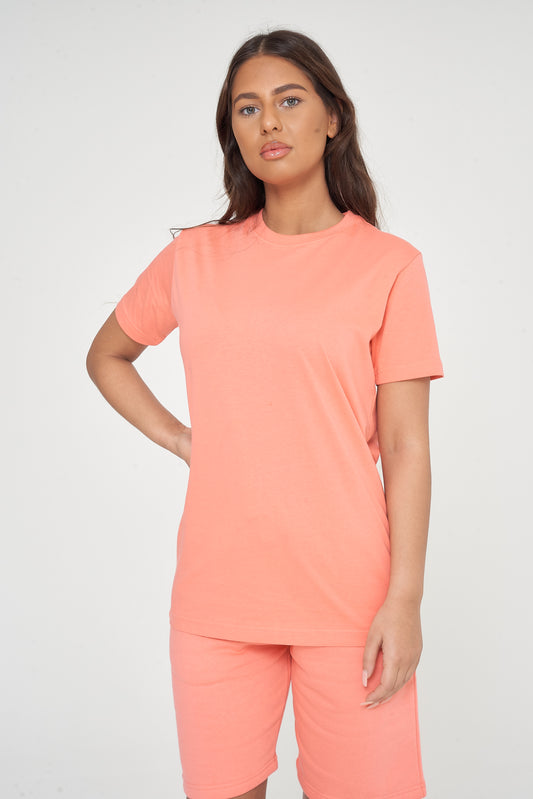 Woman wearing a basic coral t-shirt with matching shorts, front-facing pose.