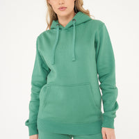 A woman wearing a basic green hoodie with matching shorts, standing in a relaxed pose. 