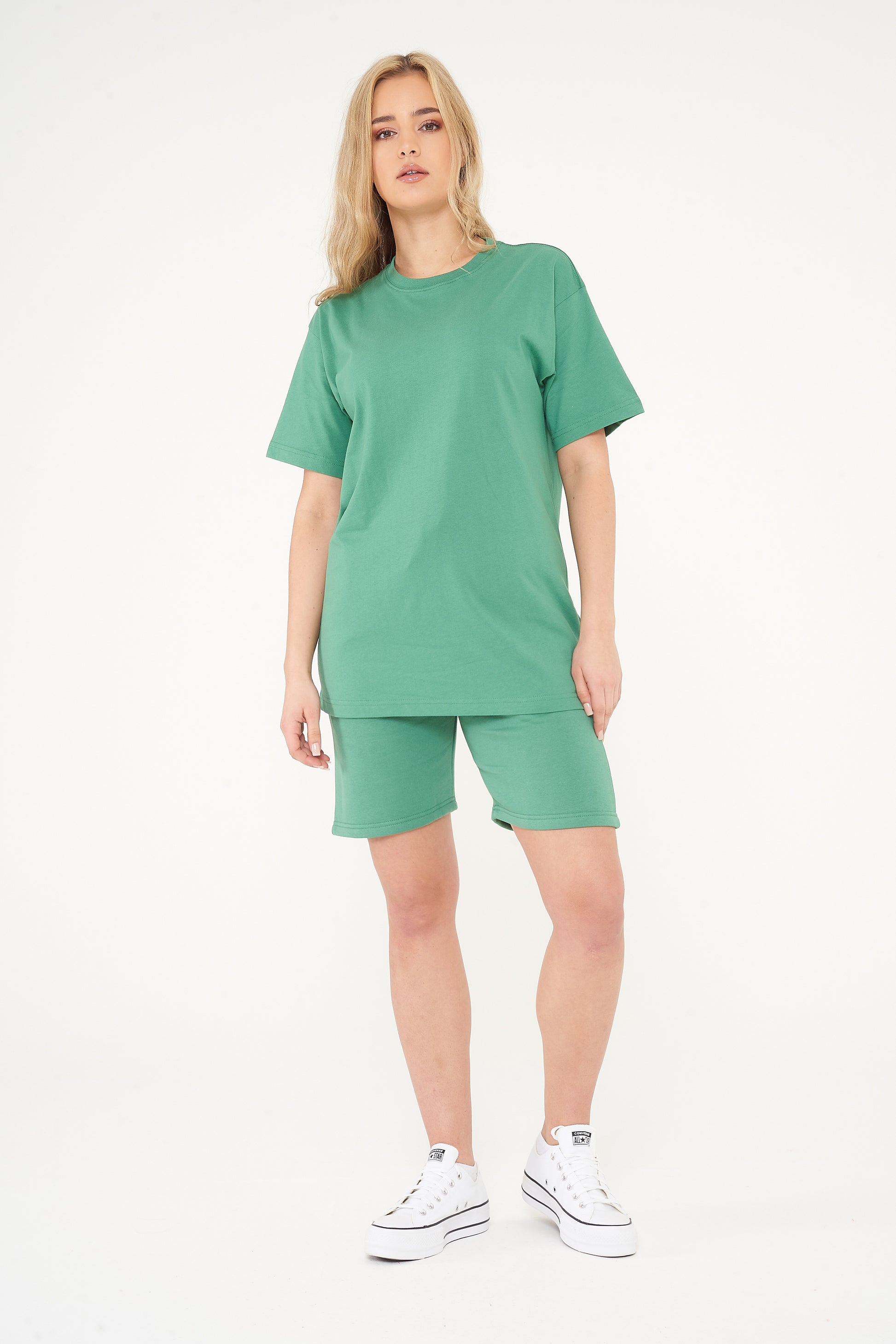 Woman standing in green shorts and t-shirt, casual style pose highlighting color and comfort. 