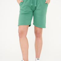Woman wearing green shorts and a matching t-shirt, front-facing. 