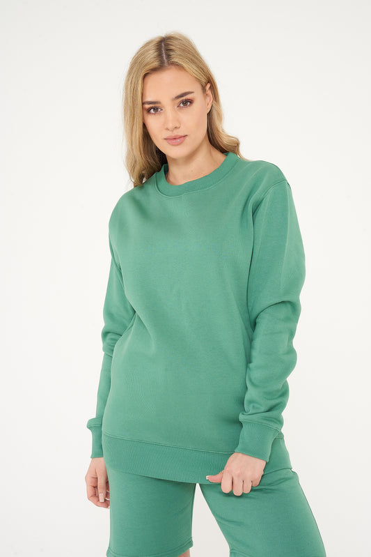 Woman modeling green sweatshirt and shorts, side view showing relaxed fit. 