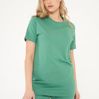 Side view of a woman modeling a green basic t-shirt and shorts, showing length and relaxed fit. 