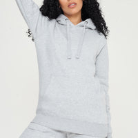 Woman in a basic grey hoodie and shorts, seated, showing everyday versatile styling. 