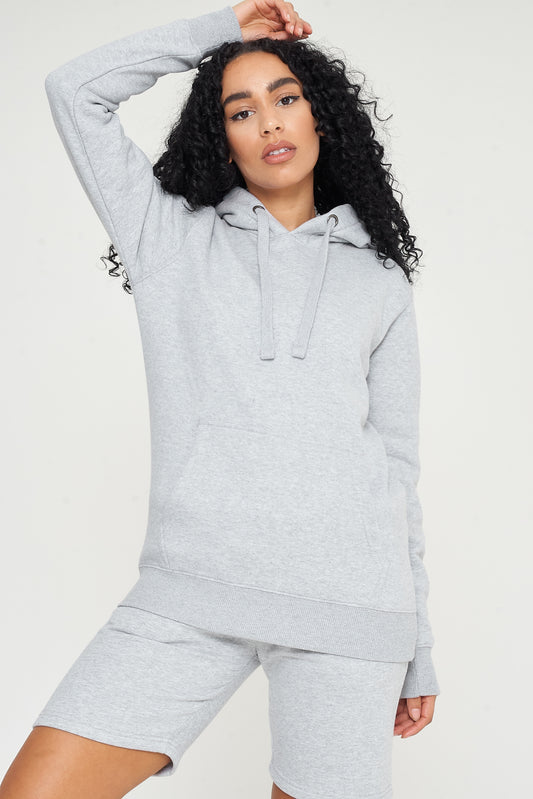Woman in a basic grey hoodie and shorts, seated, showing everyday versatile styling. 
