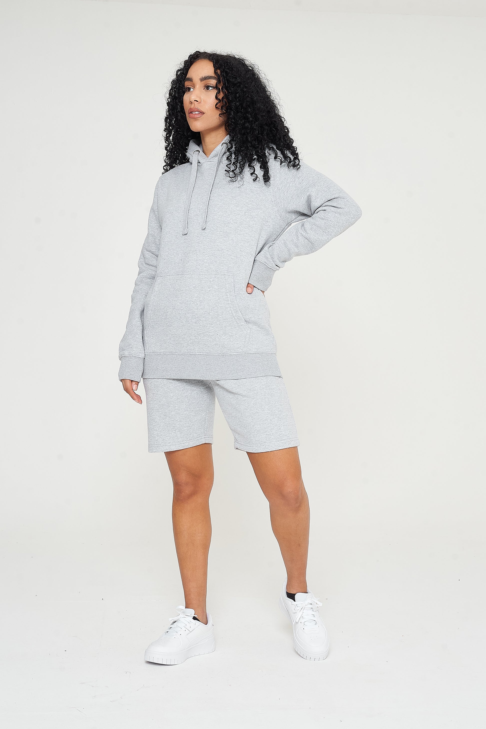 Woman modeling a basic grey hoodie, casual pose showing relaxed fit. 