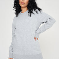 Woman standing in a basic grey sweatshirt and shorts, relaxed side pose.