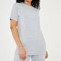 A woman standing in a basic grey t-shirt and matching shorts, a casual everyday outfit. 