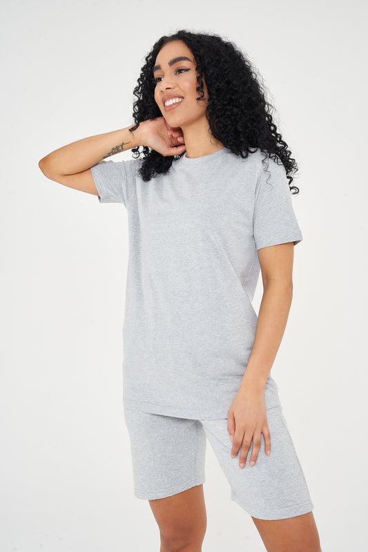 Woman modeling a grey cotton t-shirt, standing with a relaxed pose, side view. 