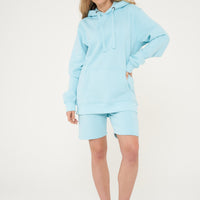 Woman wearing basic turquoise hoodie with casual shorts, front view.