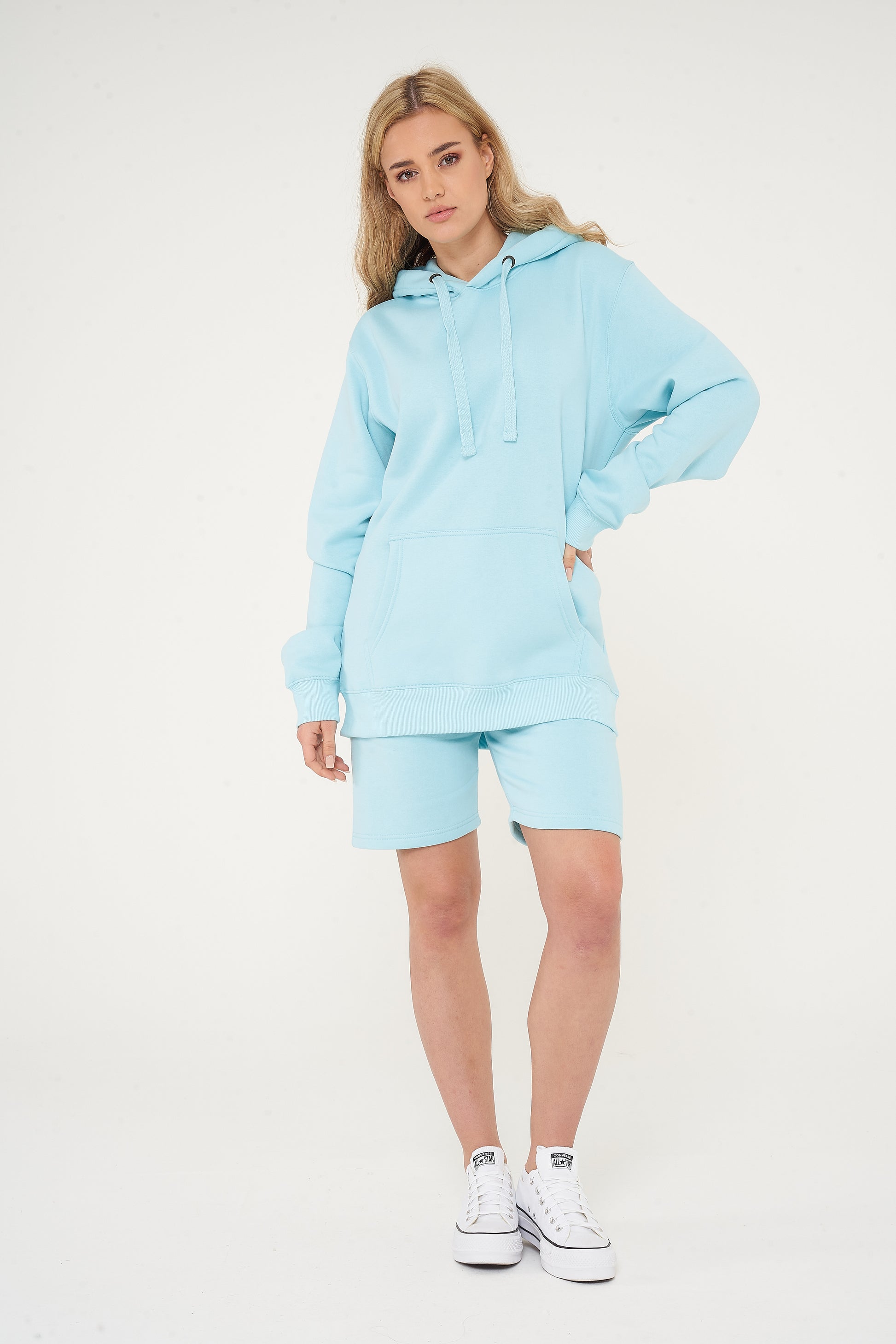Woman wearing basic turquoise hoodie with casual shorts, front view.