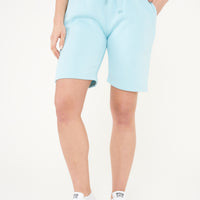 A woman wearing turquoise basic shorts with a t-shirt, front-facing.