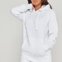 Woman posing in basic white hoodie and shorts, hands in kangaroo pocket, displaying everyday comfort.