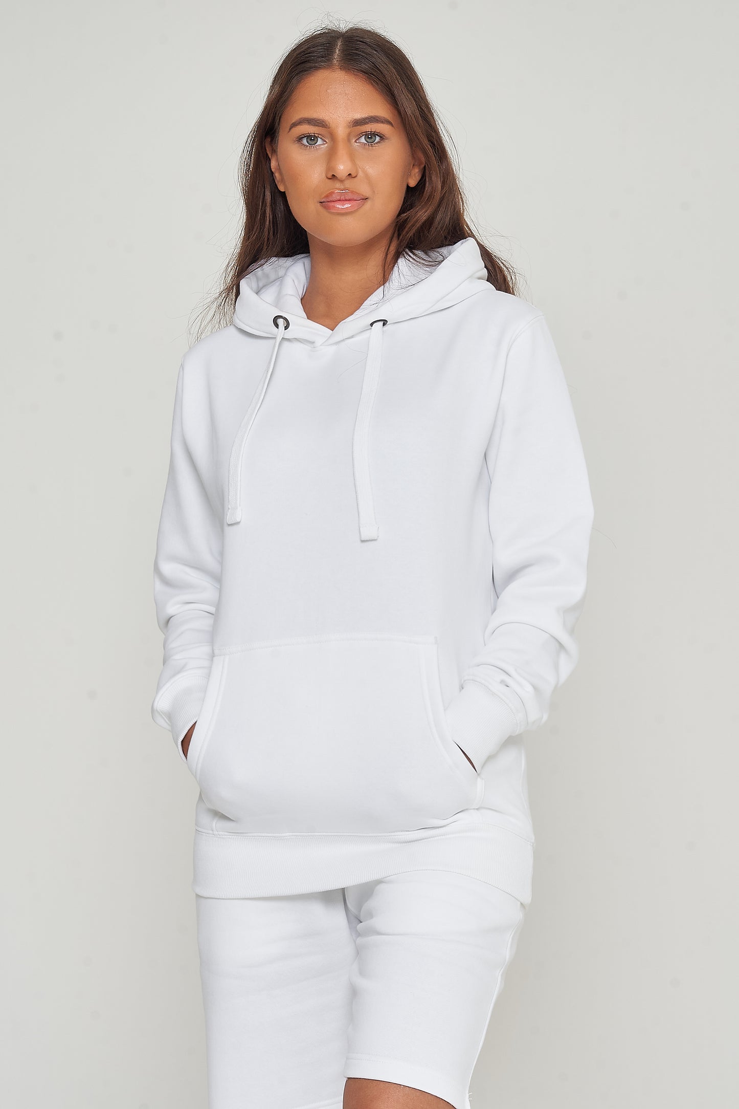 Side view of a woman in a basic white hoodie and shorts, showing relaxed streetwear style. 