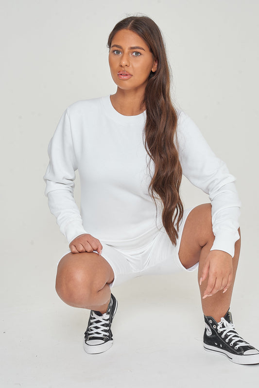 Woman wearing basic white sweatshirt with casual shorts, displaying relaxed fit and minimalist style.