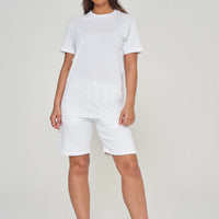 Woman standing in basic white t-shirt and shorts, showing versatile casual look.