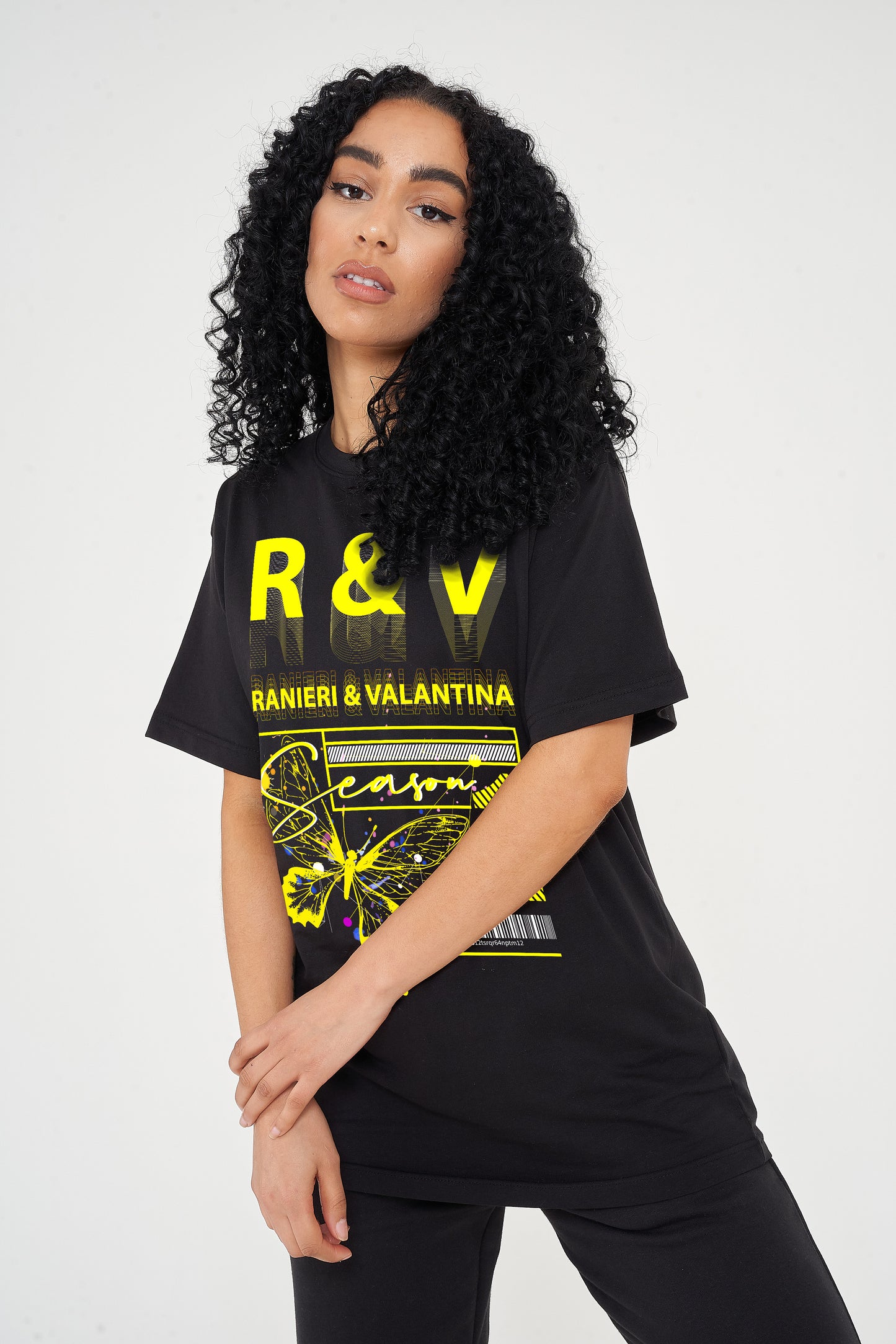 Woman wearing yellow butterfly season one graphic t-shirt styled with casual black pants.