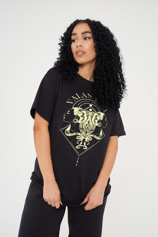 Woman wearing the black Gemini Zodiac Graphic T-Shirt styled with casual bottoms, highlighting the bold front zodiac print and comfortable oversized fit. 