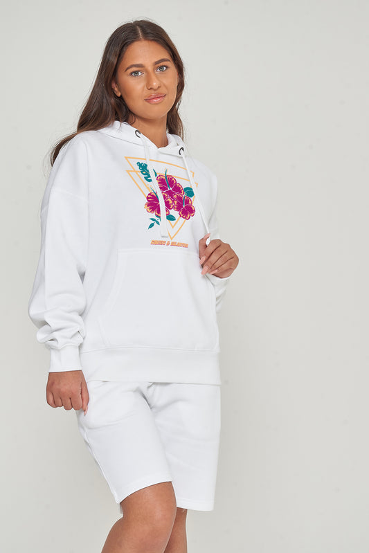 Woman wearing the white Gumamela Flower Oversized Hoodie styled with casual bottoms, highlighting the vibrant front floral print and comfortable oversized fit.