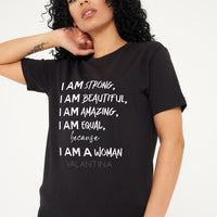 Woman wearing the black I AM A WOMAN Oversized T-Shirt styled with casual bottoms, highlighting the empowering front graphic and comfortable oversized fit.