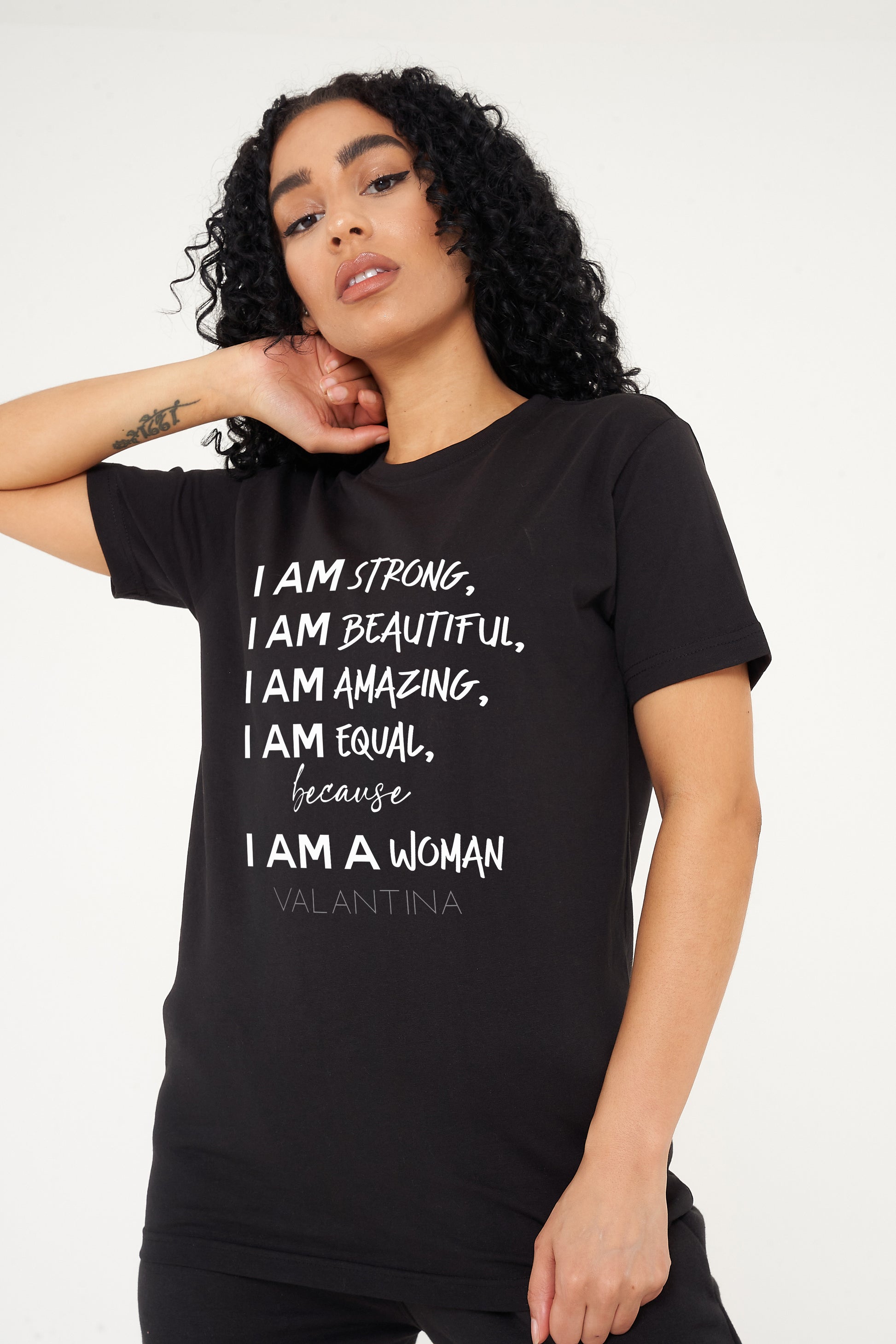 Woman wearing the black I AM A WOMAN Oversized T-Shirt styled with casual bottoms, highlighting the empowering front graphic and comfortable oversized fit.