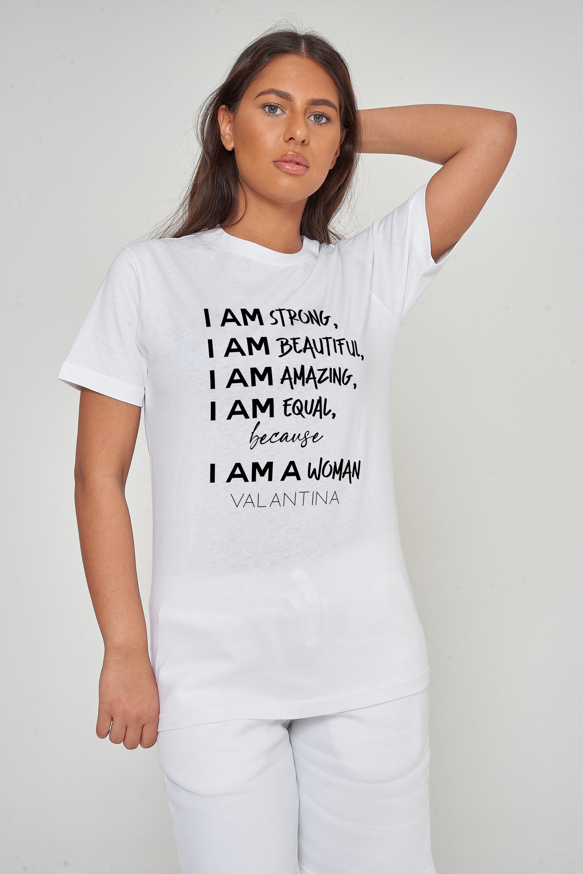 Woman wearing the white I AM A WOMAN Oversized T-Shirt styled with casual bottoms, highlighting the prominent empowering front print and comfortable oversized fit.
