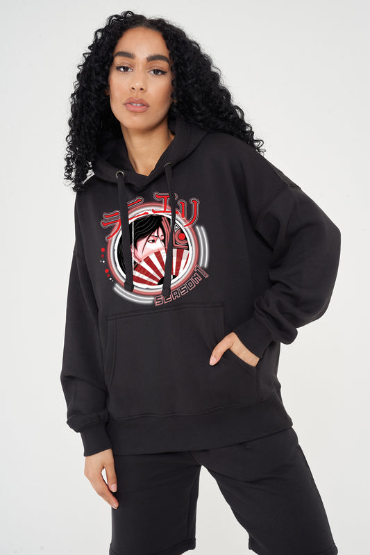 Woman wearing the Japanese Lady Season 1 Hoodie in black styled with casual bottoms, highlighting the front graphic, oversized fit, and hoodie details.