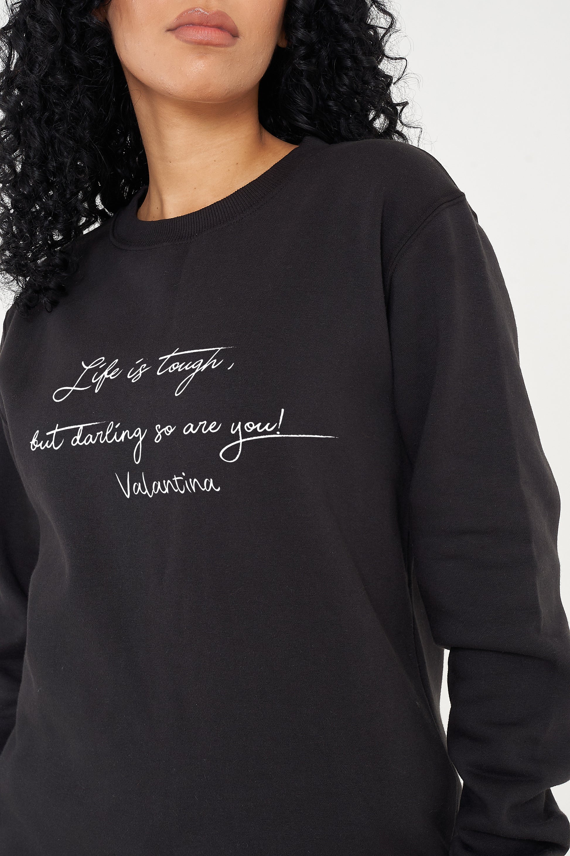 Woman wearing the black Life Is Tough Sweatshirt styled with casual bottoms, highlighting the bold front motivational print and comfortable fit.