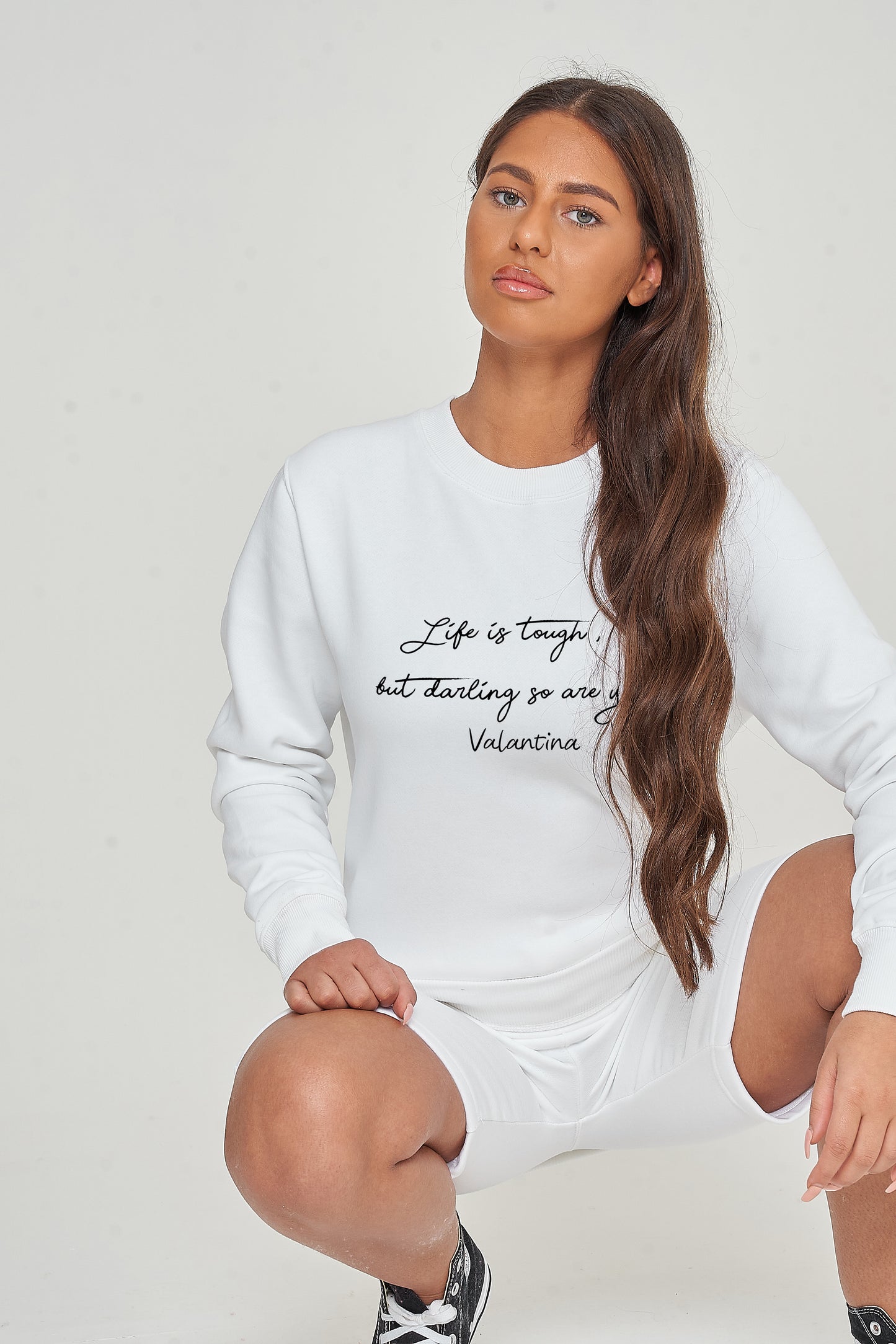 Woman wearing the white Life Is Tough Sweatshirt styled with casual bottoms, highlighting the bold front motivational print and comfortable fit.