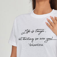 Woman wearing the white Life Is Tough T-Shirt styled with casual bottoms, emphasizing the motivational front print and comfortable fit.