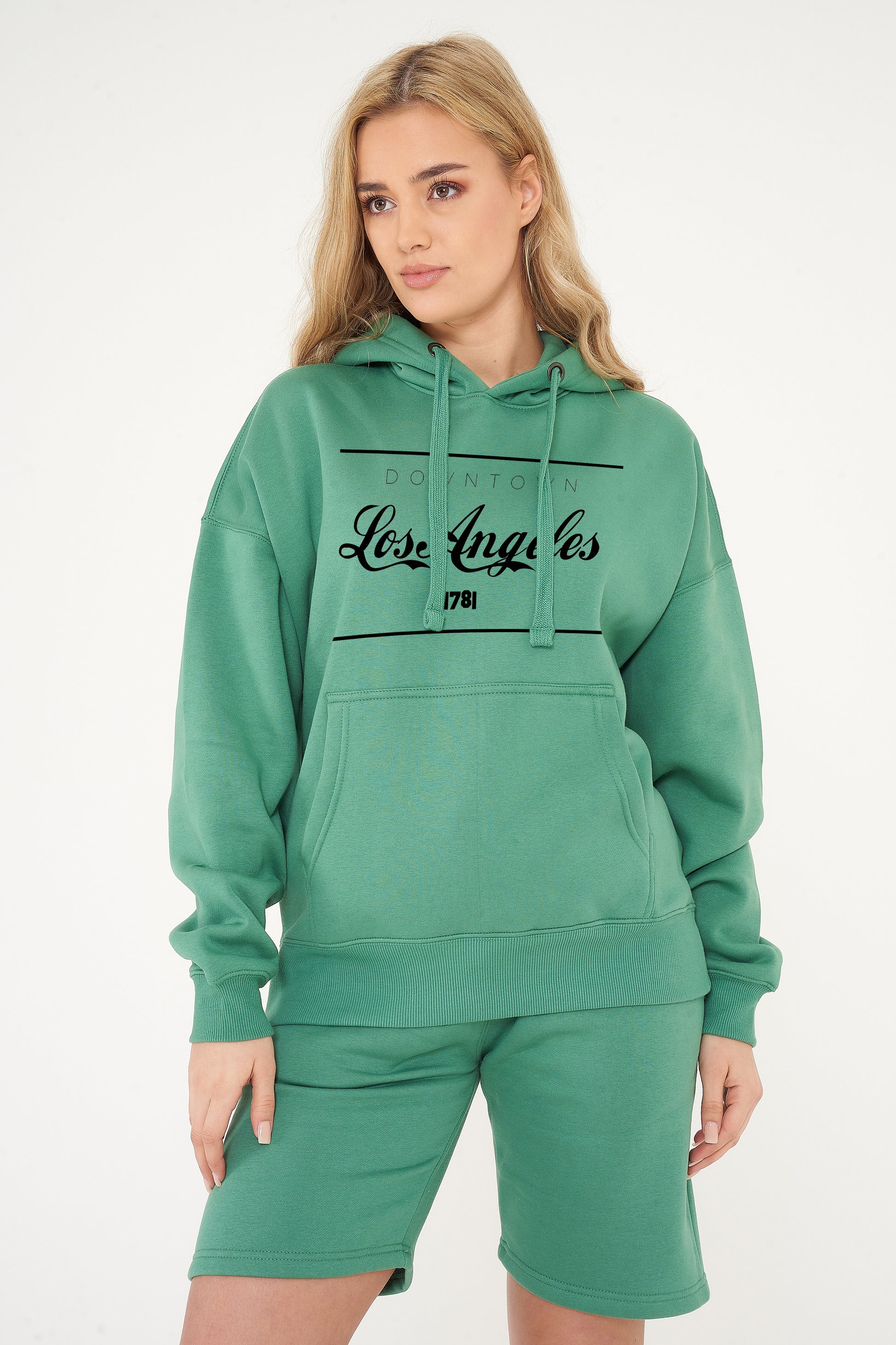 Woman wearing the green Los Angeles Oversized Hoodie styled with casual bottoms, highlighting the standout front print and comfortable oversized fit.