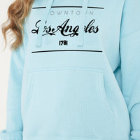 Woman wearing the turquoise Los Angeles Oversized Hoodie styled with casual bottoms, highlighting the bold front print and comfortable oversized fit.