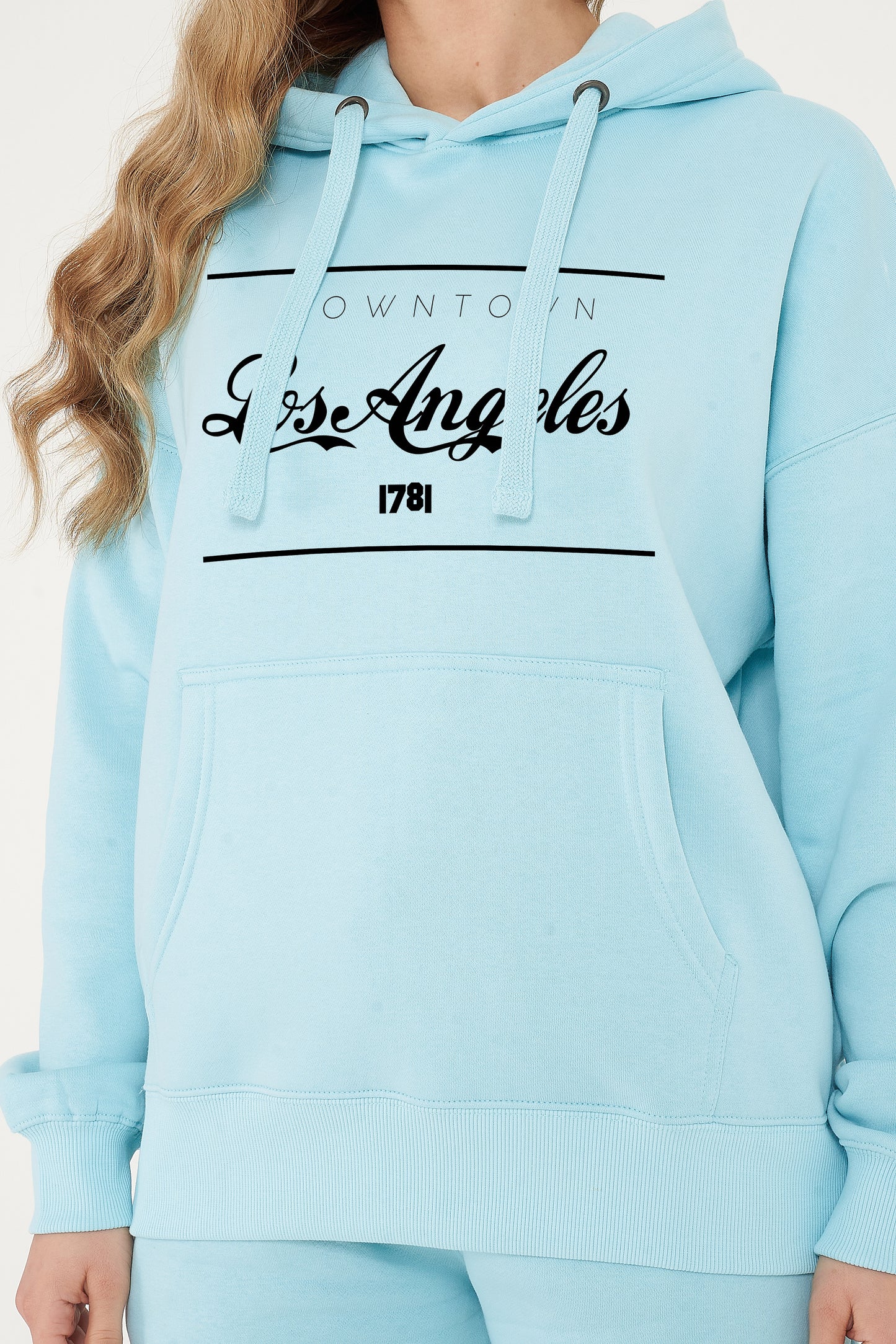 Woman wearing the turquoise Los Angeles Oversized Hoodie styled with casual bottoms, highlighting the bold front print and comfortable oversized fit.