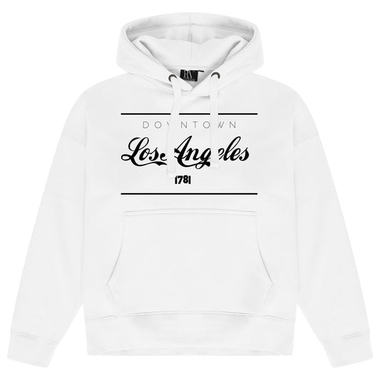 White women’s oversized hoodie featuring a bold black “Los Angeles” graphic printed centrally on the chest, adjustable drawstring hood, long sleeves, ribbed cuffs and hem.