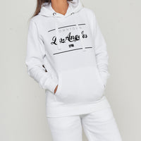 Woman wearing the white Los Angeles Oversized Hoodie styled with casual bottoms, highlighting the bold front graphic and comfortable oversized fit.